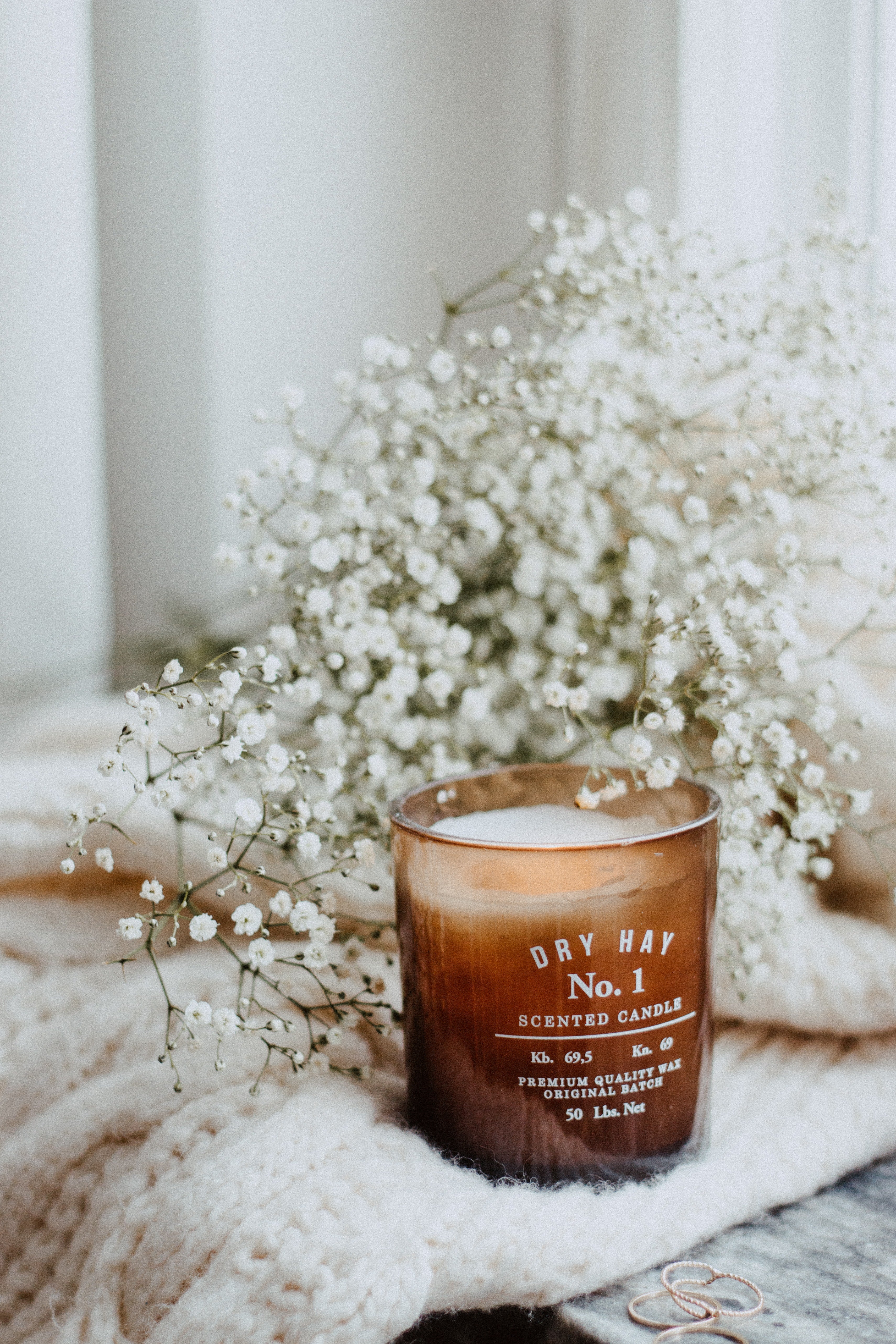 A candle and baby's breath sitting on a white knitted blanket.